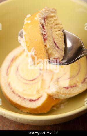Tranches de dessert Arctic Roll dans un bol avec une portion sur une cuillère. Banque D'Images