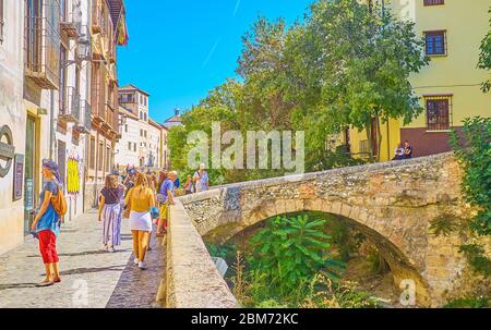 GRENADE, ESPAGNE - 25 SEPTEMBRE 2019 : les gens marchent le pont arqué Puente Espinosa au-dessus de la rivière Darro et la passerelle en pierre de la rue Carrera del Darro d'Albai Banque D'Images