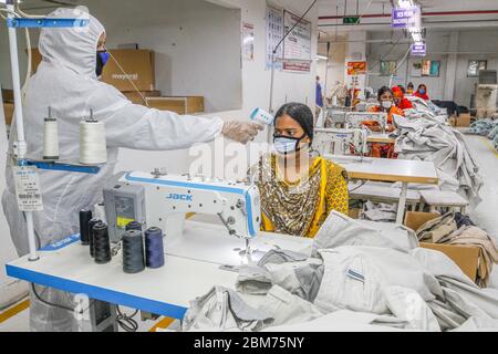 Dhaka, Bangladesh. 7 mai 2020. Un fonctionnaire vérifie la température corporelle d'un travailleur dans une usine de vêtements à Dhaka, au Bangladesh, le 7 mai 2020. Des milliers d'usines de vêtements readymade (RMG) au Bangladesh ont repris leurs activités depuis la semaine dernière à une échelle limitée. Crédit: STR/Xinhua/Alay Live News Banque D'Images