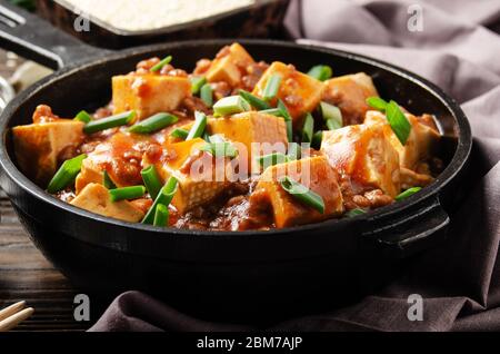 Mapo tofu dans une poêle en fonte avec ciboulette hachée de porc sauce soja poivre du sichuan ail et épices Banque D'Images