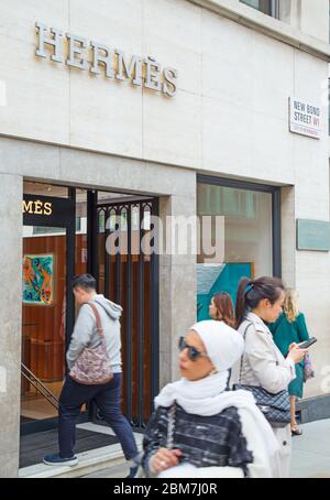 Des clients internationaux intelligents, dont l'un est asiatique, se promeaient devant le magasin de luxe Hermes sur Bond Street, dans le West End de Londres, au Royaume-Uni Banque D'Images