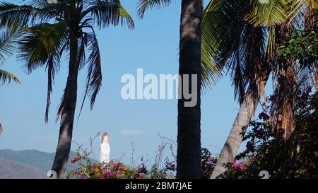 Sanya, Hainan, Chine - Paysage avec des palmiers tropicaux et la déesse de la Miséricorde situé dans la mer contre le ciel bleu dans le Centre culturel bouddhiste de Nanshan Banque D'Images