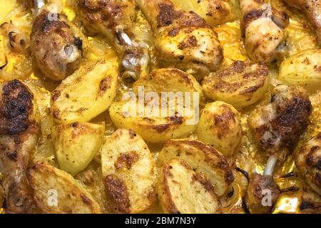 Pommes de terre et cuisses de poulet cuites au four avec croûte et oignon. Texture, fond de cuisine rustique Banque D'Images