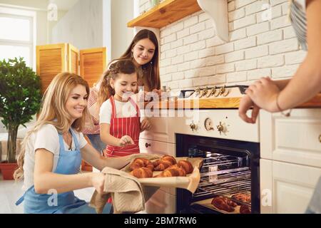 Mère et filles avec un plateau de boulangerie fraîche sont en regardant le four dans la cuisine. Fête des mères. Banque D'Images