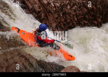 Femelle kayak de l'université pagayant au-dessus d'une cascade (Triple Step) dans un kayak Z-one sur la rivière Etive, Glen COE, Scottish Highlands, Écosse, Royaume-Uni Banque D'Images