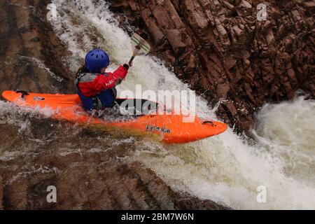 Femelle kayak de l'université pagayant au-dessus d'une cascade (Triple Step) dans un kayak Z-one sur la rivière Etive, Glen COE, Scottish Highlands, Écosse, Royaume-Uni Banque D'Images