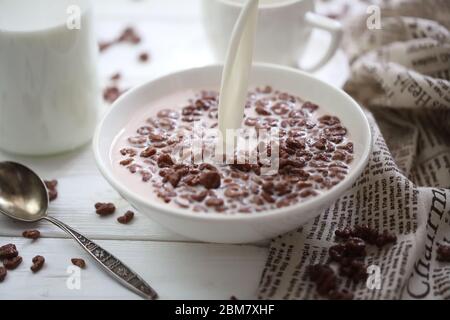 Le lait est versé dans des boules de chocolat. Céréales pour le petit déjeuner Banque D'Images