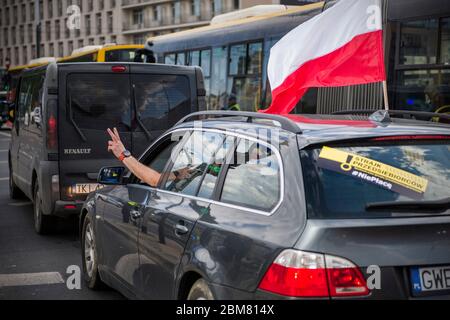 Un manifestant à l'intérieur d'une voiture avec un drapeau polonais sur les côtés, signe de victoire pendant la grève.UNE manifestation automobile initiée par le groupe, les "entrepreneurs", a organisé une grève à Varsovie pour protester contre le "gel de l'économie" dû à la pandémie du virus de la couronne. Les manifestants ont essayé de bloquer la circulation dans le centre de Varsovie. Banque D'Images