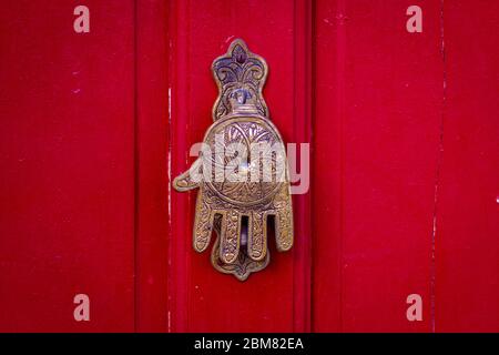 Main de Fatima, un style typiquement marocain, comme un porte de défonce sur une porte en bois rouge Banque D'Images