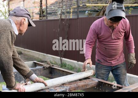 Deux soudeurs travaillent sur le chantier, homme avec son père travaillant avec le métal dans l'arrière-cour Banque D'Images