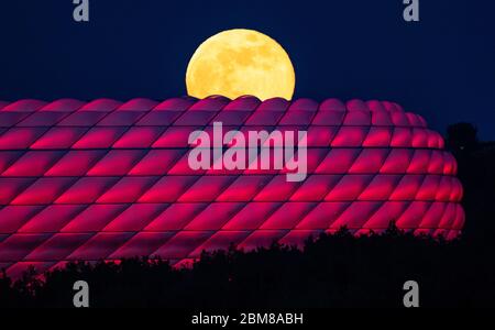 Munich, Allemagne. 07th Mai 2020. La pleine lune se lève derrière l'Allianz Arena illuminée. Crédit : Peter Kneffel/dpa/Alay Live News Banque D'Images