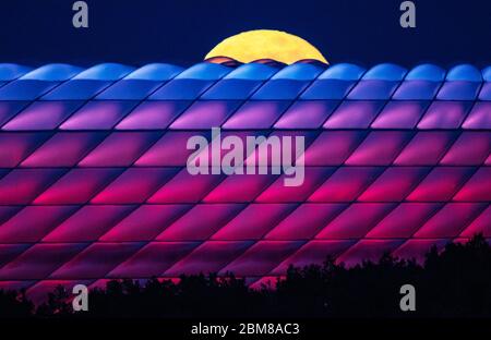 Munich, Allemagne. 07th Mai 2020. La pleine lune se lève derrière l'Allianz Arena illuminée. Crédit : Peter Kneffel/dpa/Alay Live News Banque D'Images