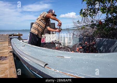 Le pêcheur artisanal Dennis Arroyo Ramírez a pêché avec une nasa et un filet depuis qu'il était enfant. Sur son bateau, sur un quai de Cabo Rojo, sur la côte sud-ouest de Porto Rico, il fixe le filet après qu’un requin en a brisé une partie. (Coraly Cruz Mejías, GPJ Porto Rico) Banque D'Images