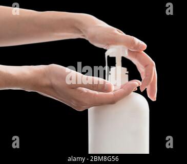 Femme mains poussant pompe en plastique savon bouteille, isolé sur fond noir avec espace de copie Banque D'Images