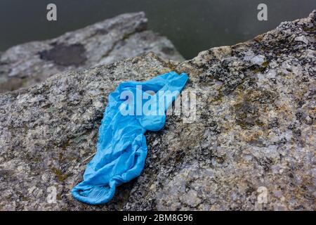 Utilisé des gants médicaux sur la pierre. Les gants jetables bleus froissés jetés sur le sol présentent des risques pour la santé publique et polluent l'environnement Banque D'Images