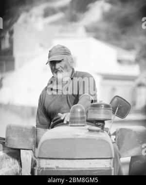 Un ouvrier agricole qui travaille sur un tracteur labourant ou labourant la terre. Préparation à la culture dans le domaine agricole. Agriculture traditionnelle en Espagne. Banque D'Images