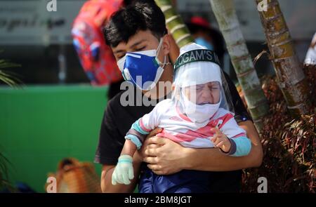 Lima, Pérou. 07th Mai 2020. Un homme portant un double masque facial tient un enfant pleurant avec un masque facial et un masque facial dans ses bras en attendant à un arrêt d'autobus au milieu de la pandémie de Corona pour qu'un autobus l'emporte dans sa ville natale. Dans la lutte contre la propagation du virus corona, le gouvernement péruvien a imposé un couvre-feu jusqu'au 10 mai. Le pays sud-américain a confirmé la mort de 58526 personnes infectées par le Covid-19 et de 1627 coronavirus. Credit: Cesar Lanfranco/dpa/Alay Live News Banque D'Images