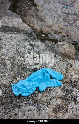 Utilisé des gants médicaux sur la pierre. Les gants jetables bleus froissés jetés sur le sol présentent des risques pour la santé publique et polluent l'environnement Banque D'Images