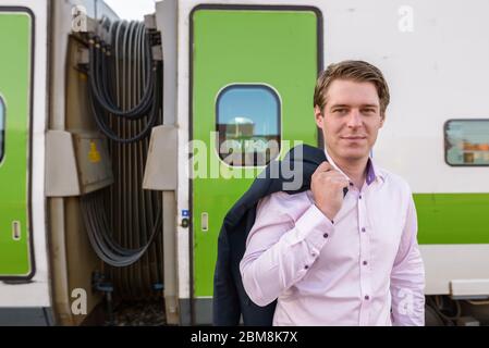 Jeune homme d'affaires beau devant le train à la gare Banque D'Images
