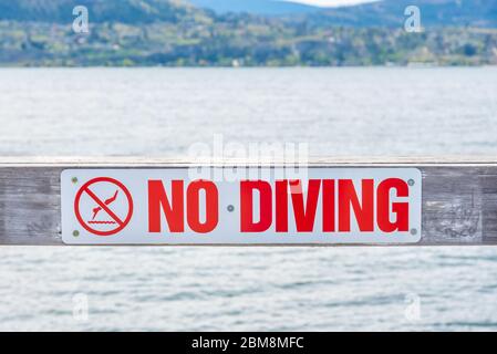 Gros plan du panneau No Diving sur la jetée avec vue sur le lac Okanagan et les montagnes en arrière-plan Banque D'Images