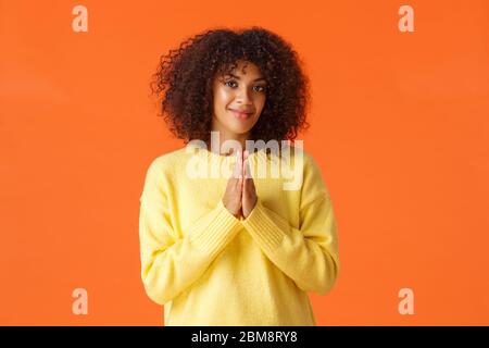 Fille se sentant relish est proche, quelque chose de bon va se produire. Une femme afro-américaine heureuse et assurée, se mord les mains et souriant, en attente Banque D'Images