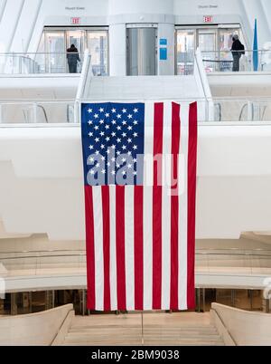 Immense drapeau américain fièrement suspendu dans un bâtiment du centre-ville de Manhattan avec accès au métro, près du World Trade Center, New York, Etats-Unis. Banque D'Images