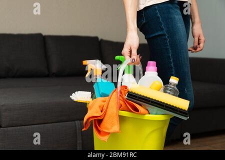 Une fille tient des détergents dans un seau sur le fond. La femme est prête à nettoyer la maison. Nettoyage dans une maison. Nettoyer et laver la maison. Une femme de ménage est c Banque D'Images