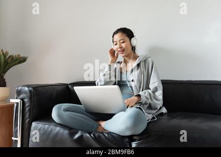 Une jeune femme asiatique utilisant un ordinateur dans le salon Banque D'Images