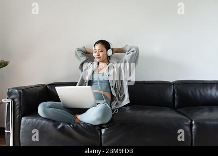 Une jeune femme asiatique utilisant un ordinateur dans le salon Banque D'Images