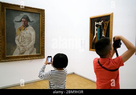 Les enfants qui prennent des photos devant l'exposition d'Arlequin assis de Pablo Picasso au Centre Pompidou.Paris.France Banque D'Images