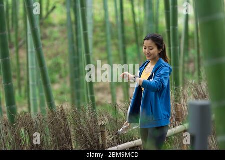 Une jeune femme asiatique marche et s'y repose dans une forêt de bambou