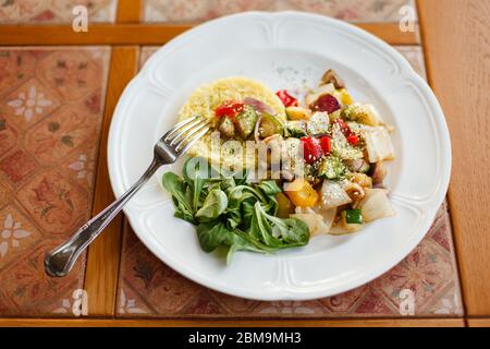 assiette blanche avec champignons et légumes frits, riz bouilli et épinards frais. sur une table en bois décorée de carreaux de céramique. vue sur le dessus Banque D'Images