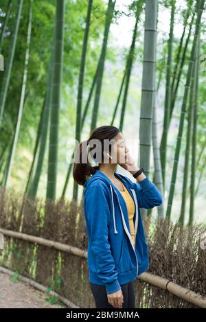 Une jeune femme asiatique marche et s'y repose dans une forêt de bambou