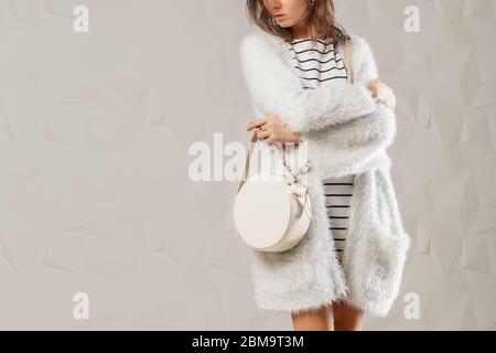 Femme élégante et tendance avec sac à main rond en cuir blanc tendance. Modèle portant un ensemble monochrome blanc. Prise de vue en studio. Copie, espace vide pour te Banque D'Images