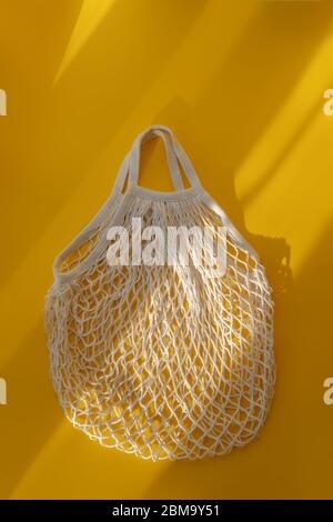 Sac vide en maille sur fond jaune vif et fort soleil. Le concept de zéro déchet. Utilisation de sacs réutilisables au lieu de cellophane p jetable Banque D'Images