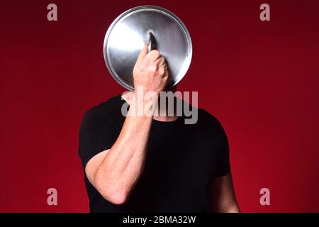 homme tenant un couvercle de pot devant son visage Banque D'Images