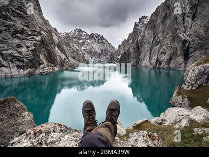 Brown chaussures militaires de randonneur en face du lac de montagne Kel Suu. Situé à proximité de la frontière chinoise au Kirghizstan Banque D'Images