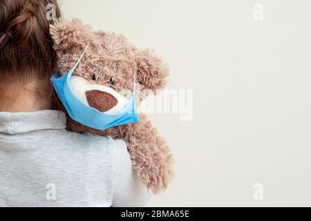 Ours en peluche avec masque médical de protection sur l'épaule de l'enfant. Concept de soins de santé et de protection contre les virus. Banque D'Images
