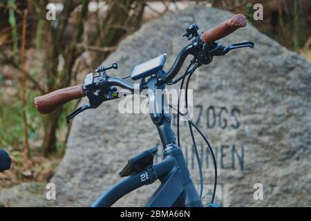 Gifhorn, Allemagne, 27 avril 2020 : guidon d'un vélo électrique stationné devant une pierre inscrite, photo concept pour la visite à vélo Banque D'Images