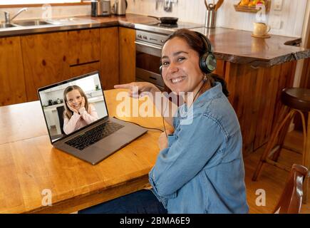 COVID-19 formation en ligne. Enseignant principal et élève en interaction dans la leçon vidéo en direct. Femme tuteur avec casque et ordinateur portable travaillant à distance depuis la maison Banque D'Images