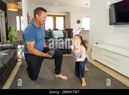 Arrêt COVID-19. Père et fille en quarantaine s'exerçant avec des haltères. Avantages de l'activité physique pendant le verrouillage. Rester à la maison, Banque D'Images