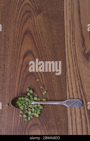 Petits pois verts dans une cuillère à café. Banque D'Images