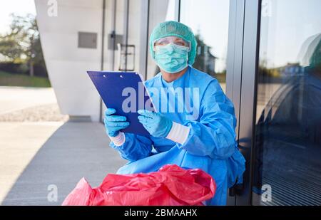 Un agent de nettoyage contrôle l'élimination des déchets dangereux en clinique pendant une pandémie de coronavirus Banque D'Images