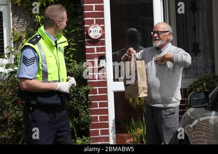 Patrick McGowan, de Collins Avenue à Dublin, remercie le sergent John O'Reilly, de la police communautaire de Finglas, après avoir reçu son médicament d'ordonnance. Les membres d'an Garda continuent de participer à une large gamme d'activités communautaires, dans un effort pour aider les gens à travers la pandémie Covid-19, y compris la livraison de médicaments pour les personnes auto-isolant, la collecte des pensions, et faire le shopping pour les gens cocooning. Banque D'Images