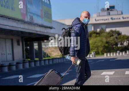 RIGA, LETTONIE. 7 mai 2020. Les ouvriers des bus portant des costumes de protection et des masques de protection du visage attendent les passagers à leur arrivée à l'aéroport international de Riga. Banque D'Images