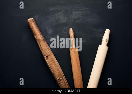 trois types de goupilles à roulettes en bois pour faire rouler la pâte sur fond noir, ustensiles neufs et très anciens, vue de dessus Banque D'Images