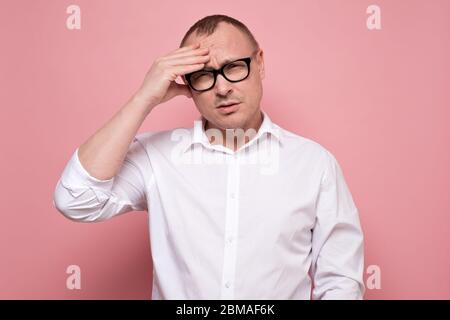 Un jeune homme stressé dans des lunettes regrettant quelque chose, regardant l'appareil photo. Banque D'Images