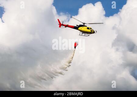 Hélicoptère volant dans le ciel versant de l'eau sur les feux Banque D'Images