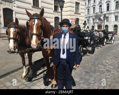 Wien, Autriche. 08e mai 2020. Adam Liko, 26 ans, qui conduit une calèche à Vienne depuis quatre ans, attend les clients avec un masque facial à côté de la calèche. (À dpa les premiers Fiakers sont de retour - mais les affaires sont extrêmement mauvais) crédit: Matthias Röder/dpa/Alay Live News Banque D'Images