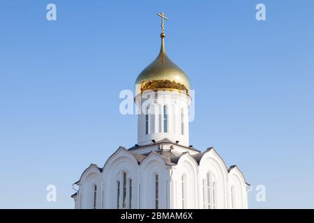 L'église est blanche avec un dôme doré et une croix russe sur le dessus contre un ciel bleu clair, un jour d'été. Le lieu de puissance et de foi des chrétiens Banque D'Images